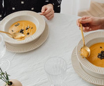 A top view of two people enjoying creamy pumpkin soup with elegant table setting.